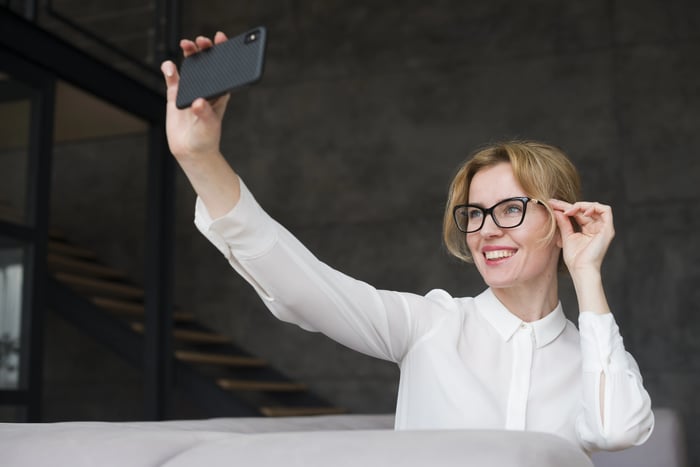 Customer testing eyeglass frames through mobile virtual try-on app while adjusting fit.