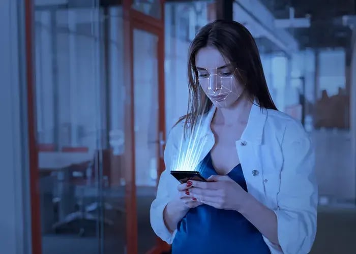 Woman using a smartphone facial scan to measure pupillary distance for virtual eyewear try-on.