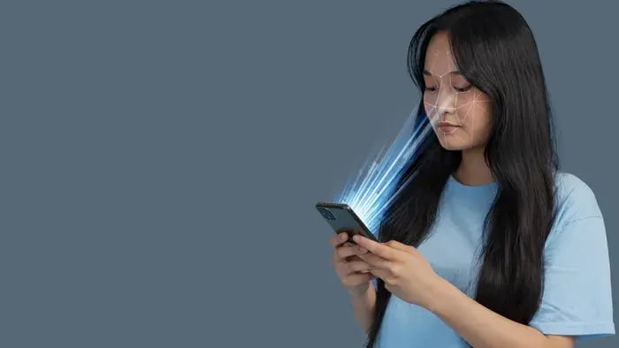 Woman using smartphone face shape detection for personalized virtual eyeglass try-on.