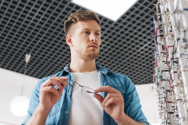 Man selecting eyeglass frames in an optical store.