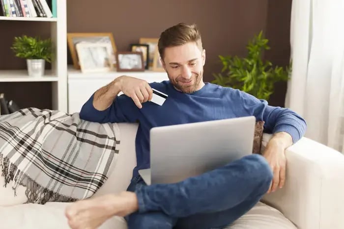 Customer completing online eyewear purchase on laptop after testing frames digitally.