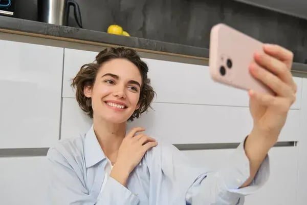 portrait-d-une-jeune-femme-assise-sur-le-sol-de-la-cuisine-avec-un-telephone-prend-un-selfie-sur-un-smartphone-avec-une-application-fil-1