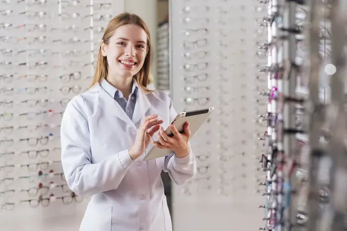 Female optometrist in eyewear store leveraging digital tools to enhance customer experience.