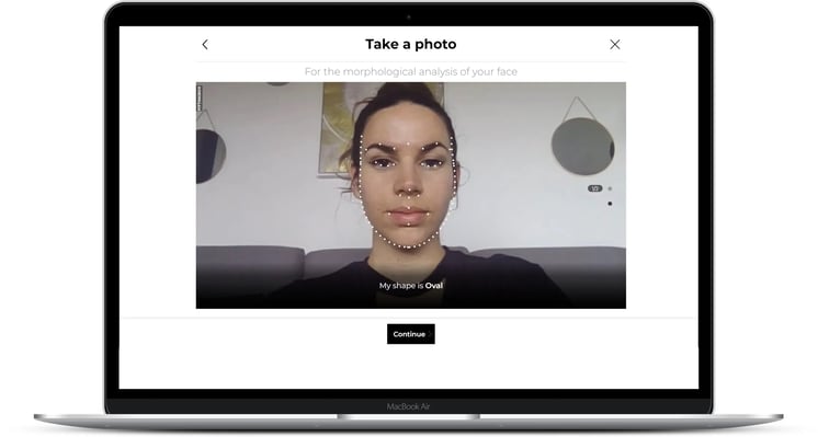 Laptop screen showing a face-shape analysis tool for eyewear, outlining a face and identifying ‘Oval’.