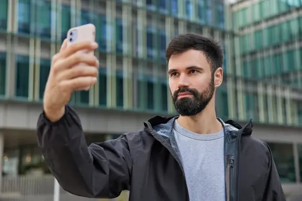 hombre barbudo haciéndose un selfie con gafas en la ciudad